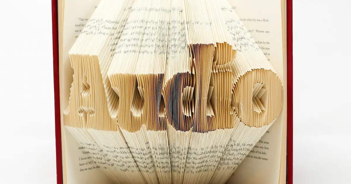 オーディオブックをイメージするため、紙の本の複数ページを折り紙のように折ってAudioの文字を形成している画像